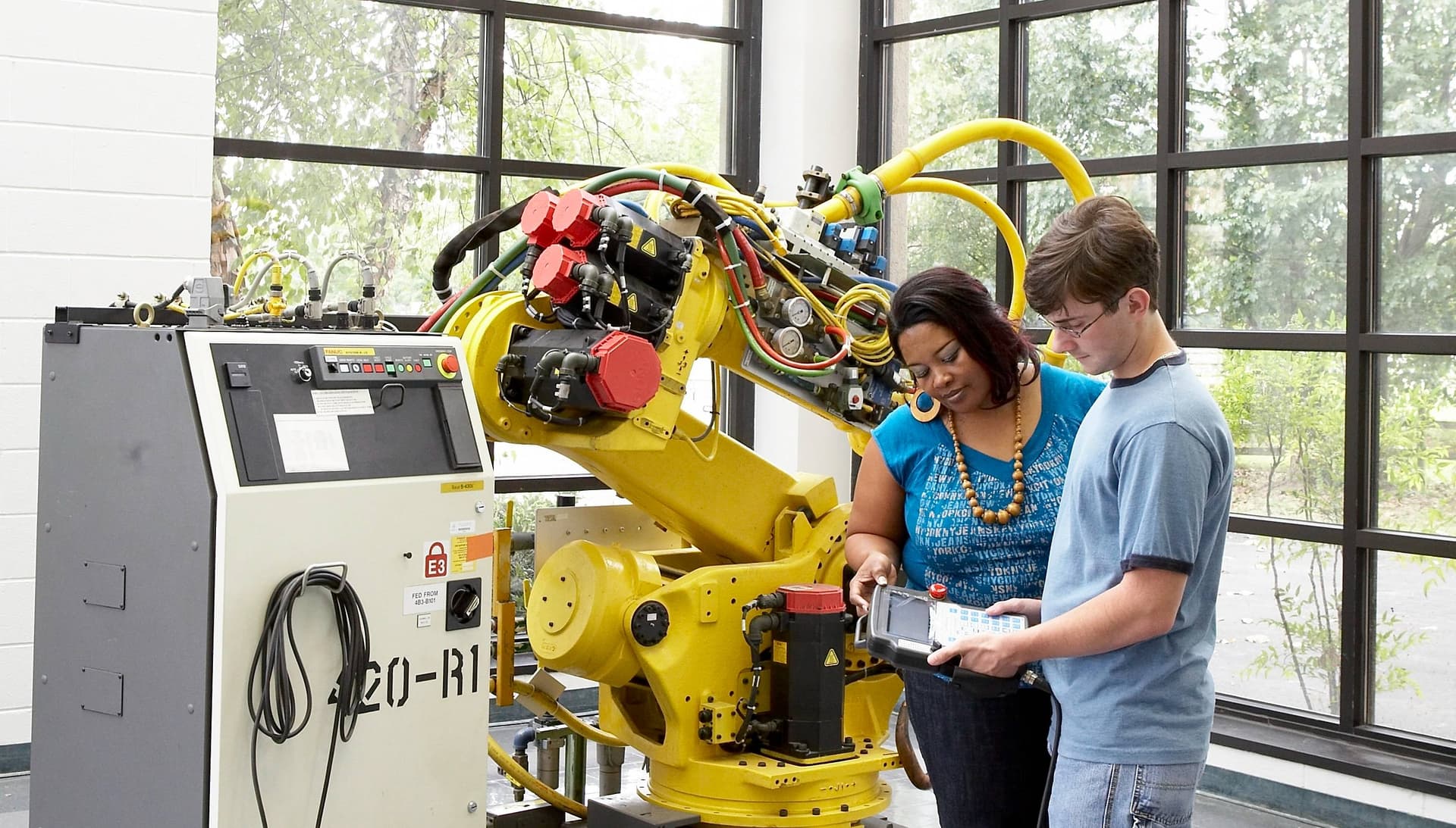 Students programming an industrial robot arm